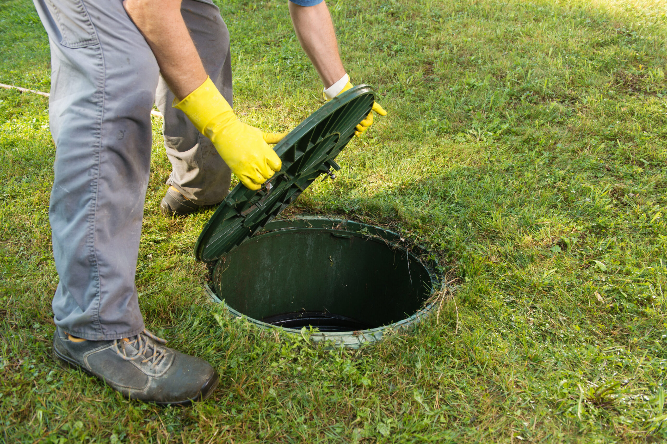 Opening septic tank lid. Cleaning and unblocking septic system and draining pipes.